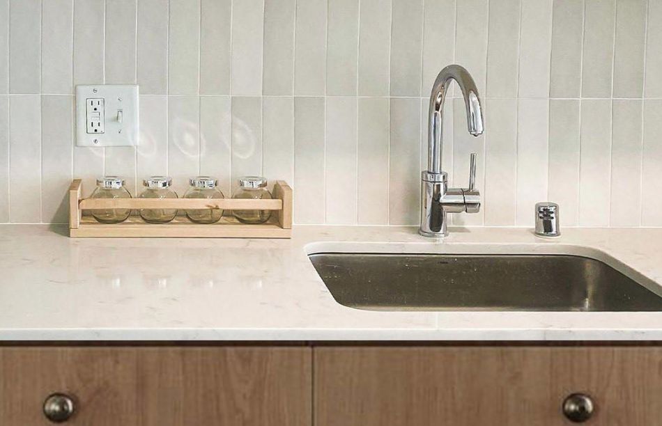artist rendering of kitchen with medium brown cabinetry, quartz counters, and stainless steel sink closeup