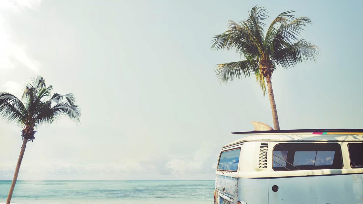 Oceanside beach lifestyle with Volkswagen van, surfboard and palm trees